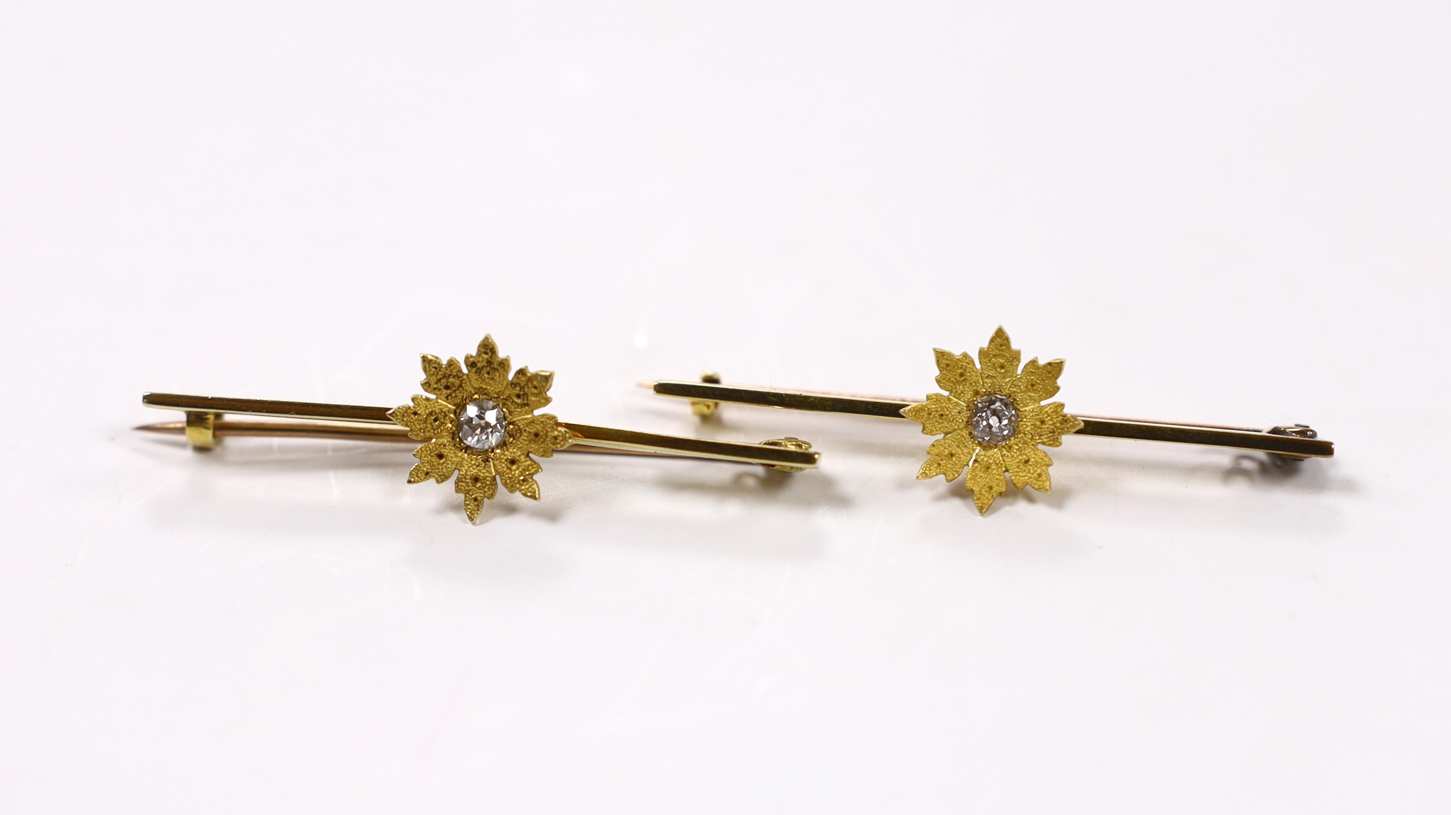 A pair of early 20th century yellow metal and single stone diamond set flower head bar brooches, 44mm, gross weight 6.2 grams.
